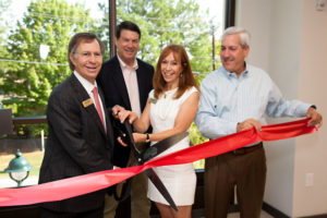 Jack Halpern, Mayor Rusty Paul, Carolyn Oppenheimer, and Councilman Andy Bauman smile as they cut a large red ribbon